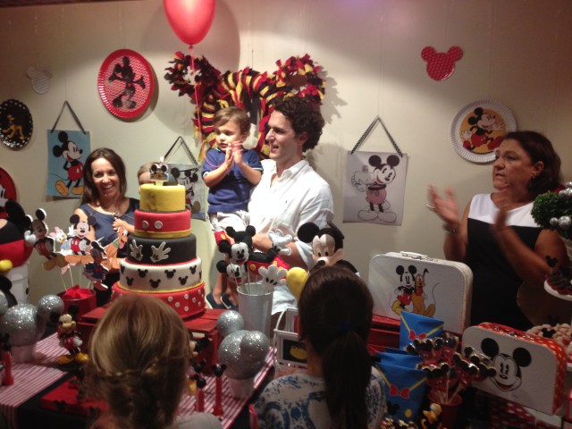 The birthday boy in his dad's arms with mom and little brother beside them. Behind the dessert table.